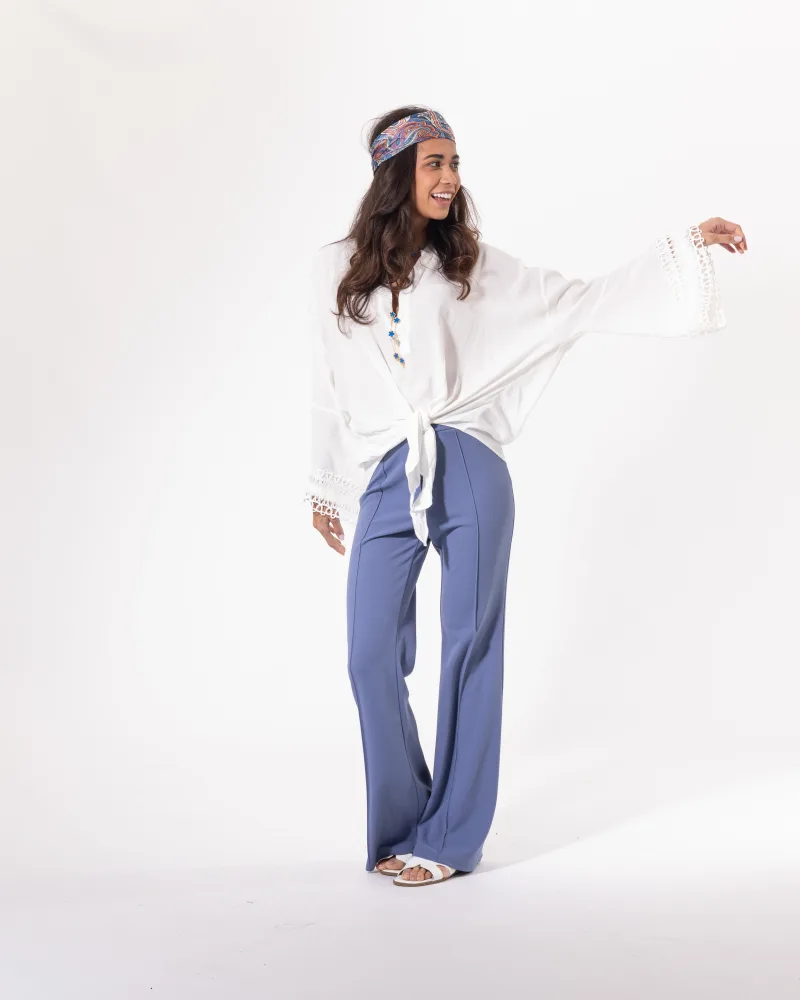 Blouse blanche Licorne Passion portée avec pantalon bleu, manches évasées en dentelle et nœud à la taille