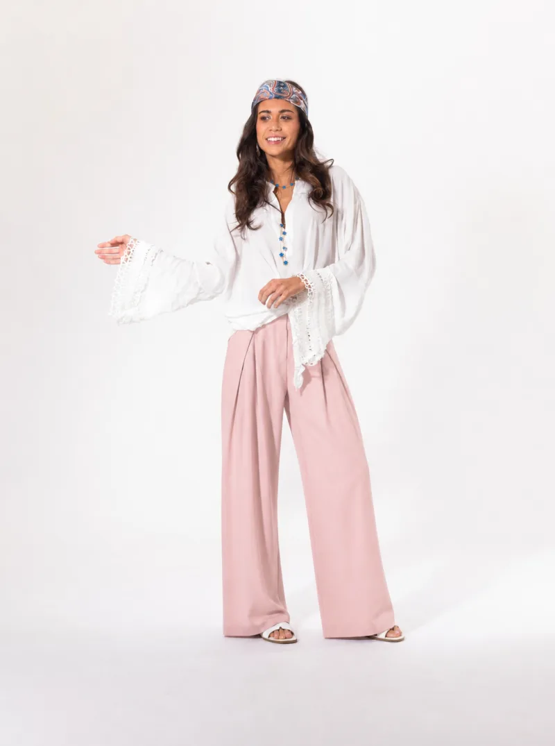 Blouse blanche Licorne Passion portée avec pantalon large rose, manches évasées en dentelle ajourée